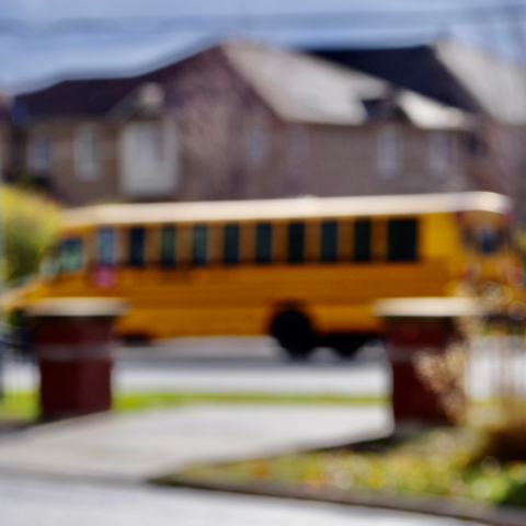 Blurry School bus, on a blurry residential street, in a sunny Thursday.