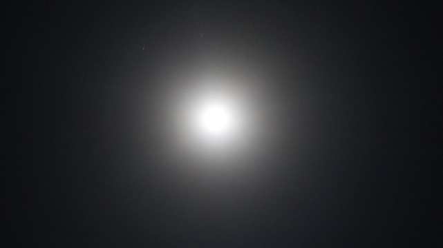 a blinding white light created by the supermoon with a grey background
