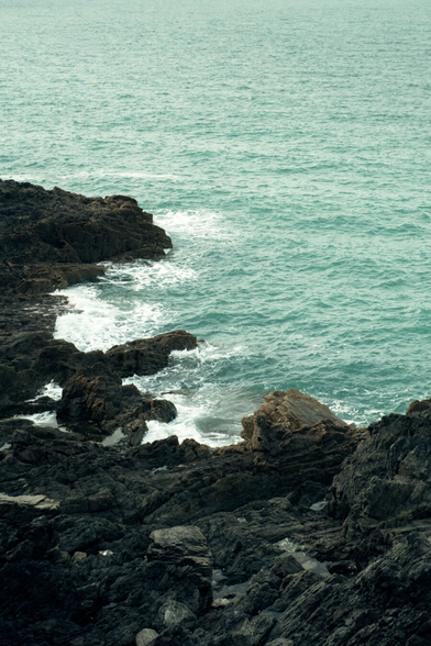 Coast of black rocks and light blue sea
