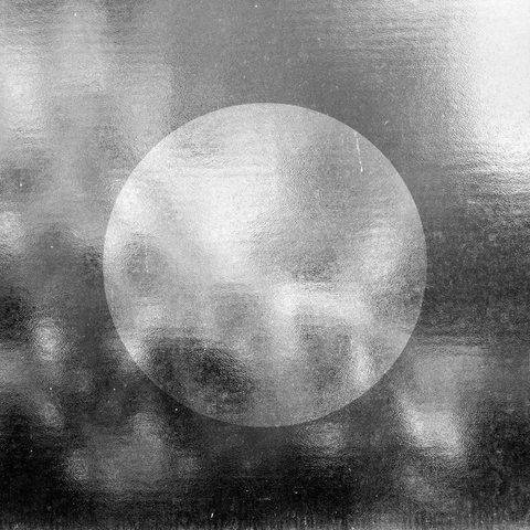 An abstract black and white glass texture with a white circle in the centre representing a moon.