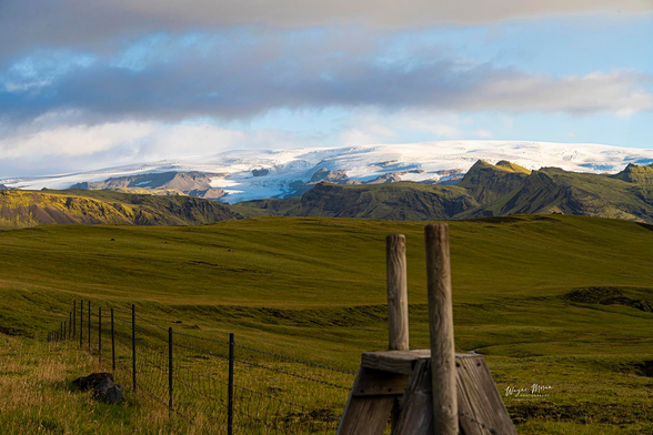Mýrdalsjökull and Katla from the West Road to Vík Iceland

Soft golden light spills across rolling emerald fields, leading the eye toward the immense ice cap of Mýrdalsjökull resting atop the famous Katla volcano. Jagged volcanic ridges rise like ancient sentinels, carved by fire and time, contrasted against the brilliant white glacier glowing beneath shifting clouds.

In the foreground, a weathered wooden stile and wire fence whisper of rural Icelandic life. Simple. Honest. Rugged. These structures mark the boundary between open pasture and the wild, where sheep roam freely in summer before the autumn réttir brings them home.

This moment captures the quiet strength of Iceland's southern wilderness. It is a landscape shaped by ancient eruptions, deep valleys, powerful ice, and the enduring rhythm of life on the edge of nature’s raw power. Standing here, approaching Vík from the west, you feel the land breathe. You feel history underfoot. You feel the freedom and wonder that only Iceland can give.

Image:
https://fineartamerica.com/featured/myrdalsjokull-and-katla-from-the-west-road-to-vik-iceland-wayne-moran.html

Read more:
https://waynemoranphotography.com/blog/chasing-light-across-iceland-our-21-day-adventure/

#Mýrdalsjökull  #Katla #Mountains #vik #Iceland #nature #travelPHotogrpahy #Landscape #art #fineart 

#ayearforart #buyintoart