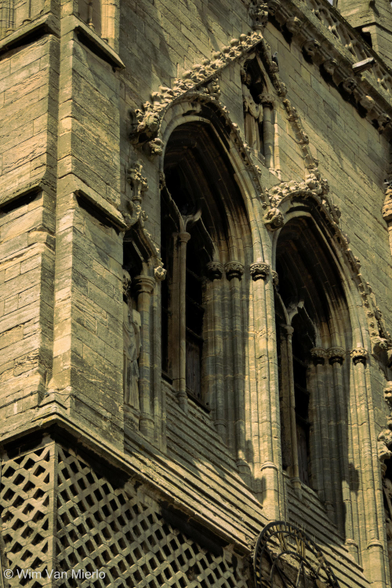 A closely-cropped detail of the church spire showing two arched windows in the sunight.