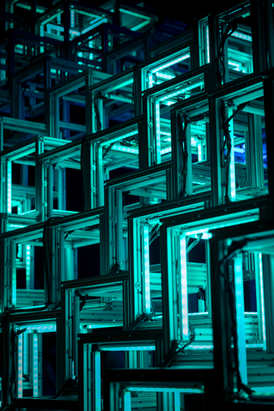 Kunstwerk bestaande uit open kubussen waarvan de ribben met groen/blauw light verlicht zijn.