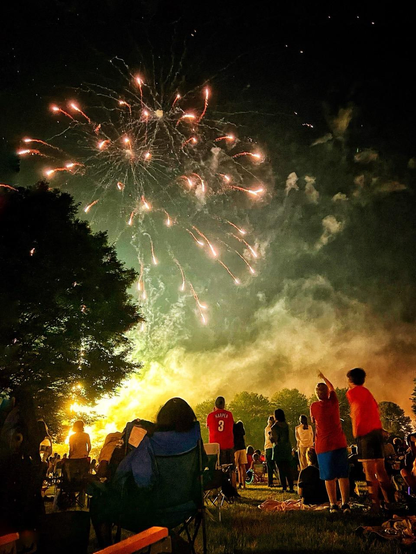 A crowd gazes upwards to a fireworks display 