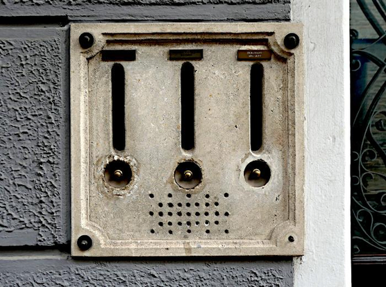 Foto van drie brievenbussen met daaronder belknoppen  in stenen plaat aan muur