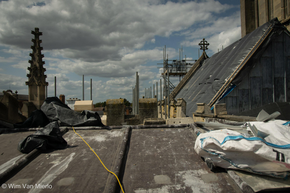 The rooftop of the church during construction work in the sunlight and with a sky full of white-grey clouds.