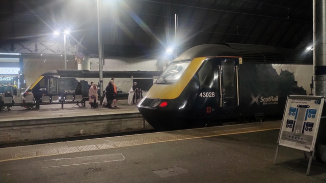 Looking across several platforms and tracks at night in Glasgow's Queen Street Station, a pair of intercity trains awaiting their next passengers