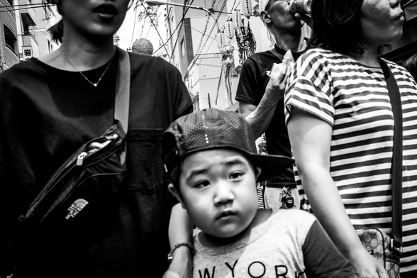 Nen envoltat pels seus pares amb una gorra amb la visera a l'esquerra.