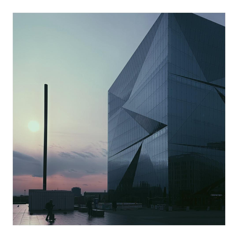 Pastellfarbener Himmel neben einem würfelförmigen Gebäude mit gebrochener Fassade 