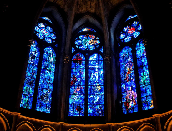 Three-panel stained glass window in Gothic cathedral, glass mostly blue in color with shades of red and green