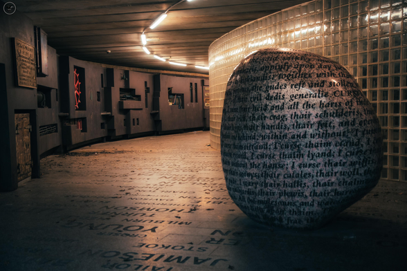 Rock art installation in under pass with glass cube walls and writing in stone floor 