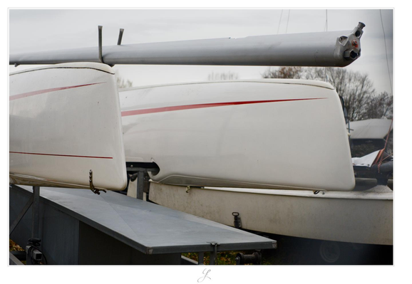 Two white hulls of a sports catamaran with thin red stripes are stored upside down on a boat trailer. The mast is fixed above and between the two hulls. The view is from the front, at an angle towards the bow tips. The sky is gray and mostly unstructured. The colors are very muted, as is typical for November in Germany.

AI disclaimer: Using my work, its meta data, written or derived description to create media with or train AI based systems is prohibited.