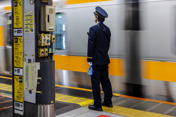 A train platform operator in uniform on duty at Shinjuku station in Tokyo (Japan). Each image features a different posture and gesture of the officer.