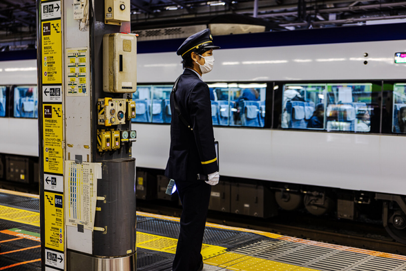A train platform operator in uniform on duty at Shinjuku station in Tokyo (Japan). Each image features a different posture and gesture of the officer.