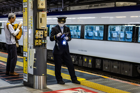 A train platform operator in uniform on duty at Shinjuku station in Tokyo (Japan). Each image features a different posture and gesture of the officer.