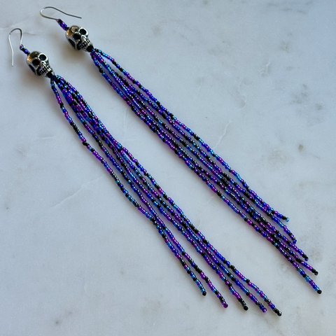 The same pair of dangle earrings laying on a marble background
