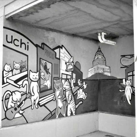 A black-and-white film photo. A view of a partial mural showing cats hanging out at local businesses with the State Capitol in the background in Austin, Texas. Sunday, November 16, 2025.