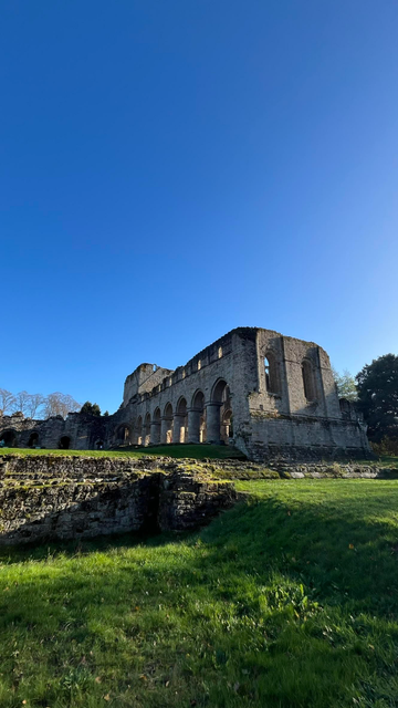 An exterior shot of the ruins of Buildwas Abbey, taken facing east.  The sky is clear and blue, green grass is visible in the foreground. 