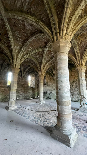 The interior of the Chapter House (some call this the East Range),  the vaulted roof is supported on four pillars and a square tiled floor is between the pillars.