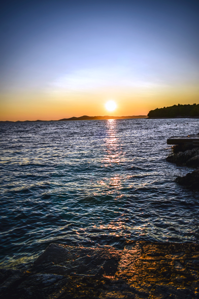 A Sunset at the sea, hills can be seen in the distance