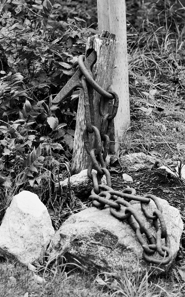 Old log clearing chain draped across a driveway post