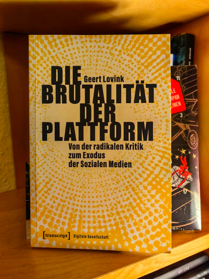 Das Buch "Die Brutalität der Plattform" von Geert Lovink in einem Regal.