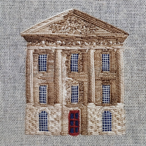 Stitched artwork depicting the central front portico of Chatsworth House in Derbyshire. There are four full height columns each with multipaned windows between them on the three floors. The central ground floor has a red door instead of a window.