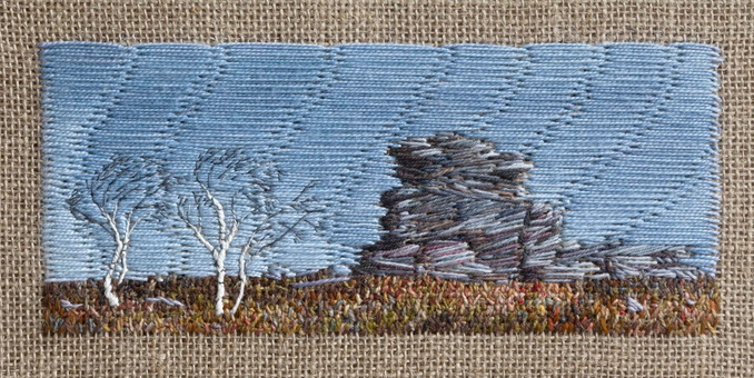 Stitched artwork depicting a gritstone outcrop in autumnal coloured moorland with two bare silver birch trees to the left. The trees are bent due to the prevailing wind. The sky is blue.