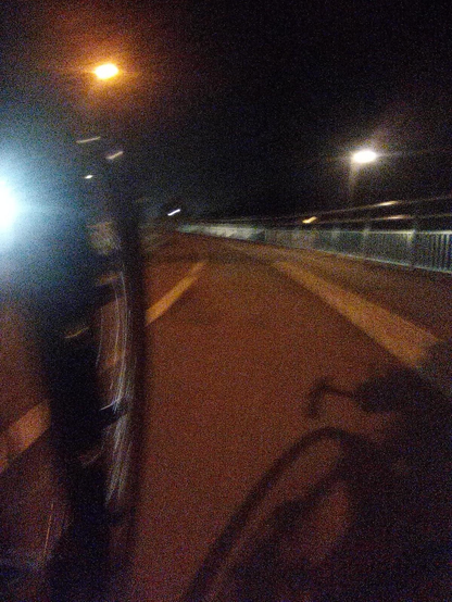 Photo de haute qualité dans la très basse qualité ,o)

Roue de vélo avec rayons inox qui brillent la nuit tels des objets magiques, piste cyclable, lumières de la ville, ombre du vélo et cycliste.
On devine les grooooos disques de 203mm.
L'image est sableuse tant il y a du grain lié au mauvais appareil photo.

Pour les personnes aveugles, vous m'en voudrez pas si je fais pas toujours d'aussi complètes descriptions.