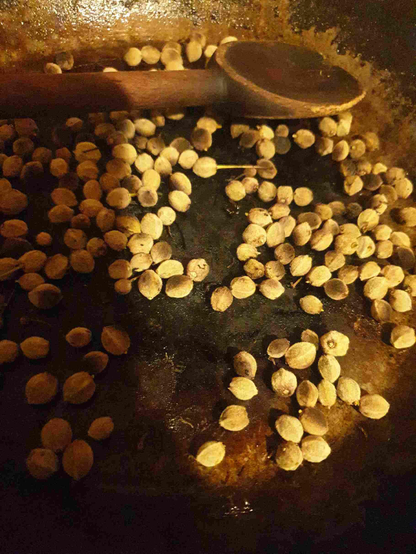 Graines de tilleul torréfiées, dans une casserole, avec une grosse cuillère en bois, et une lumière très spéciale, dorée.
Beaucoup de texture aussi.