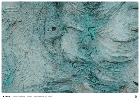 콘크리트 벽에 옥색으로 칠해진 페인트. 거칠게 칠해진 모양에 초점이 맞춰져 일부는 흐리게 보임