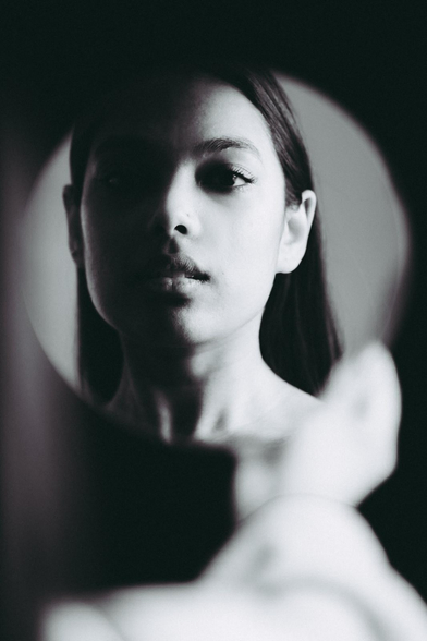 Mujer morena reflejada en espejo.