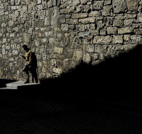 Una persona apoyada en la pared al sol