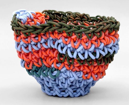 a small, colorful porcelain vessel by Jeremy Brooks that has been made by crocheting long strands of clay