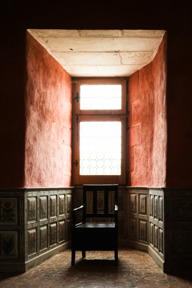 A wooden chair in a lit corner of a room