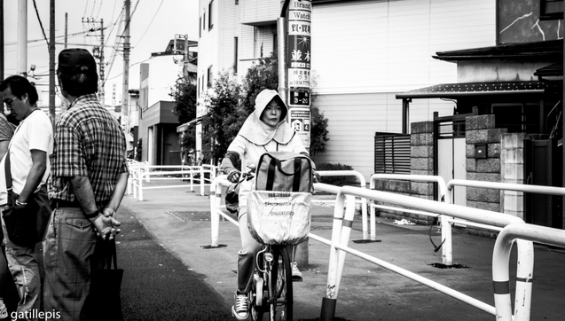 Dona amb bicicleta amb caputxa per protegir-se del sol.