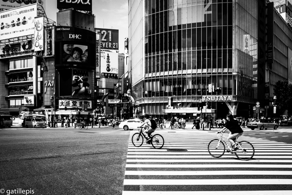 Dos ciclistes travessant el famós encreuament de Shibuya a Tòquio.