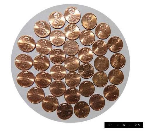 36 round US pennies arranged in 3 concentric circles with a single penny at the center.  The pennies are fairly new so their thin copper cladding is rather shiny.  The last penny was minted on Nov 12, 2025 -  a mere 232 years after the first one.  There are allegedly some 300 billion still in circulation (or about 875 per American).  I hope to live long enough to collect them all (or at least my share of 875 - whichever comes first).  
