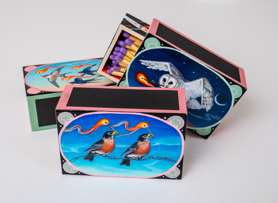 three matchboxes with birds with burning matches in their beaks