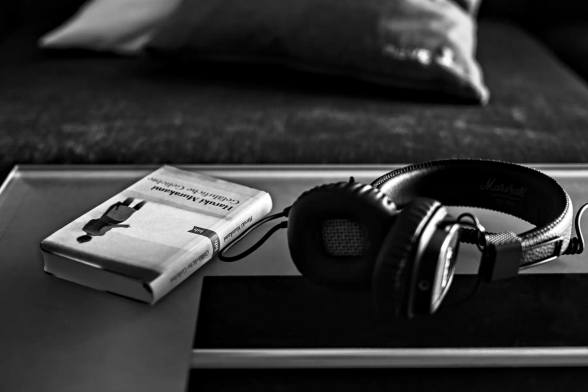 Auf einem Glastisch vor einem gemütlichen Sofa mit Kissen liegt ein Buch von Haruki Murakami: "Gefährliche Geliebte". Daneben ein Kopfhörer. 