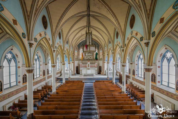 The photo shows a breathtaking view inside an abandoned church. Pews stretch toward the altar under arched ceilings with intricate designs 