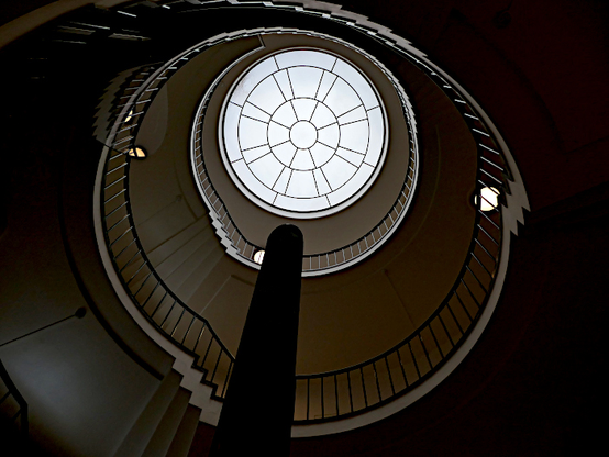 Foto van koepel met rond raam en wenteltrap van onderen gezien