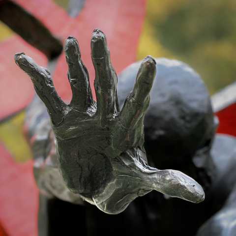 Close-up photo of the open hand of a steel statue, with the head in the background