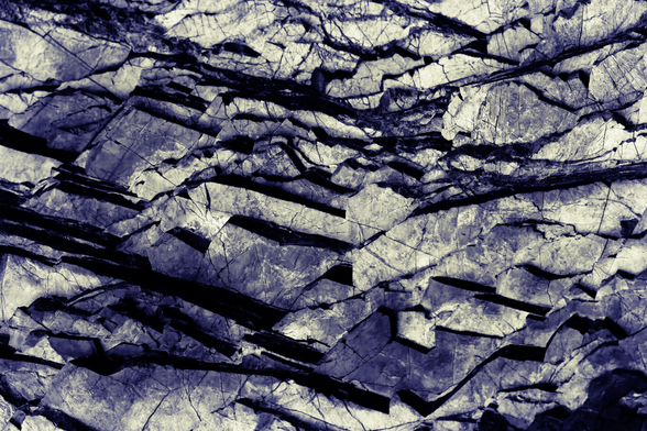 Geological rock layers in thin shale sheets, seemingly extending endlessly in all directions even though it's a close-up shot of rocks.