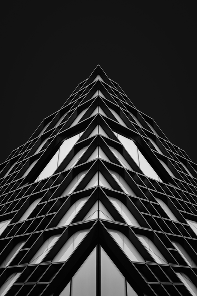 A black and white symmetrical photo of a modern building with a black background.