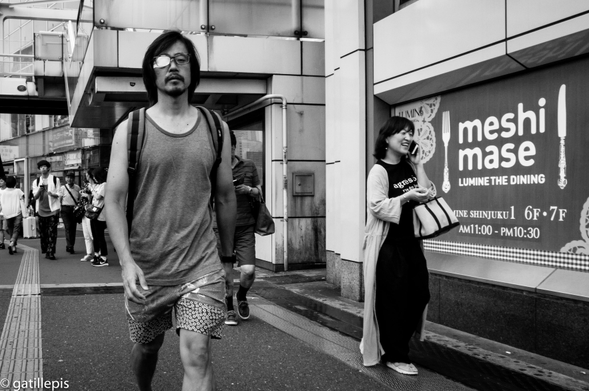 Home amb samarreta i pantalons curts, i un ull tapat pels carrers de Shinjuku.