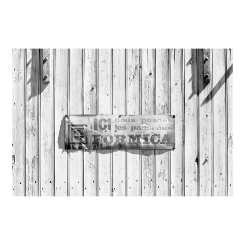 A sign on a barn door reads: ‘Here we install Formica panels’. (Version françæ) Panneau sur æn porte de grange où on peut lire: 'Ici nous installons les panneaux Formica.'