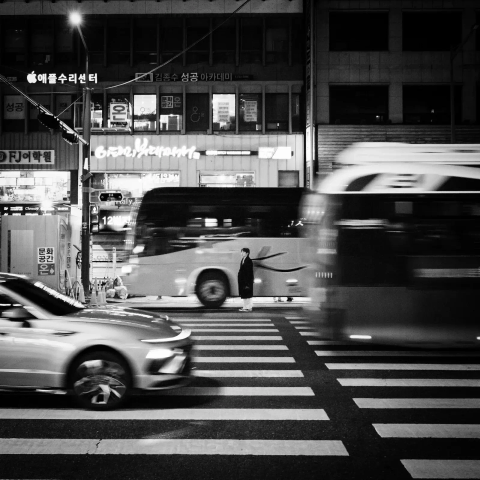 Man waits in a crosswalk in the middle of the traffic at night