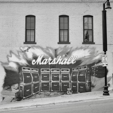 A black-and-white film photo. A large mural of a Marshall stack is featured on the side of an old building in downtown Austin, Texas. Sunday, November 16, 2025.