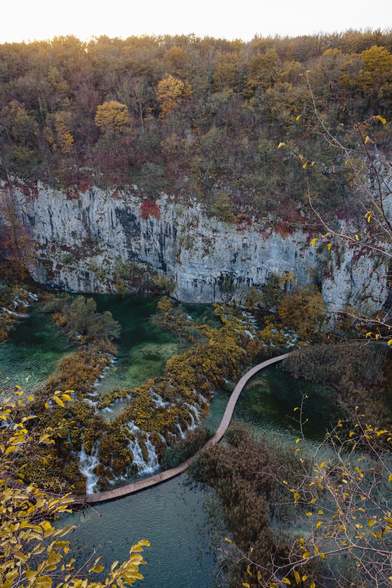 A photo taken from above, showing waterfalls, forests, and a footbridge crossing the river.